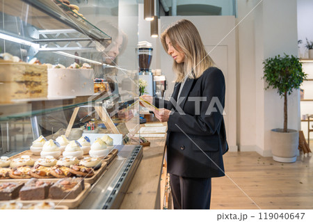 Focused coffee shop female owner inspecting establishment before opening, attentively checking menu. Focused coffee shop female owner inspecting establishment before opening, attentively checking menu. 119040647