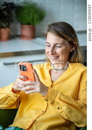 Pleased woman with smile looking to screen cellphone scrolling web spending relaxed weekend at home Pleased woman with smile looking to screen cellphone scrolling web spending relaxed weekend at home 119040687