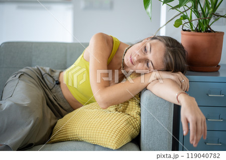 Tired dreaming woman leaning on armrest of sofa resting at home. Thoughtful female relaxing on couch 119040782