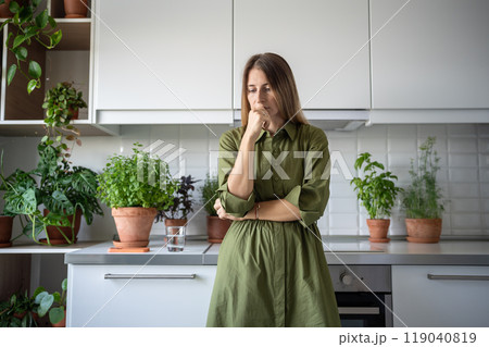 Disappointed thoughtful worried woman sadly looking thinking of problem standing at home on kitchen. Disappointed thoughtful worried woman sadly looking thinking of problem standing at home on kitchen. 119040819