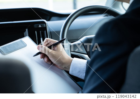運転席で書類を書く男性の手元 運転席で書類を書く男性の手元 119043142