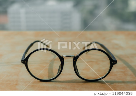 Eyeglasses on wooden desk with city view. 119044059