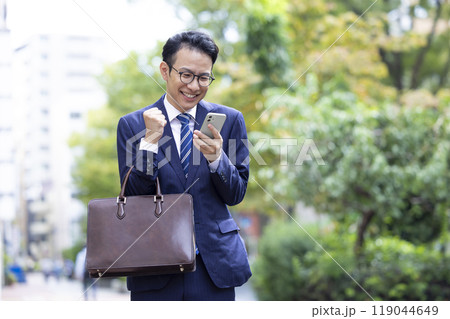 ビジネス スマホを見てガッツポーズをするミドル男性 ビジネス スマホを見てガッツポーズをするミドル男性 119044649