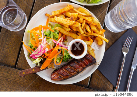 Juicy roasted duck magret served sauce framboise, french fries and vegetables 119044896