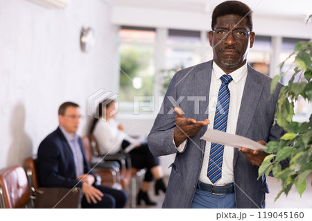 Upset adult man with documents standing in reception 119045160