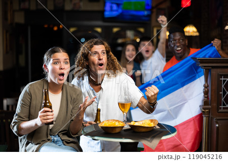 Couple cheering in sports bar against background of fans with flag of Serbia and Montenegro Couple cheering in sports bar against background of fans with flag of Serbia and Montenegro 119045216