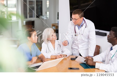 Male doctor speaks at meeting of colleagues and tells reports on condition of patients. 119045553