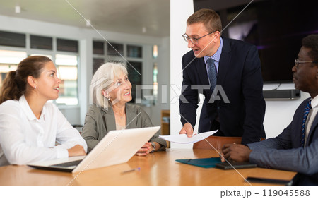 Positive business partners engaged in conversation sitting around table Positive business partners engaged in conversation sitting around table 119045588