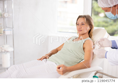 Doctor administering intramuscular injection in upper arm of female patient 119045774