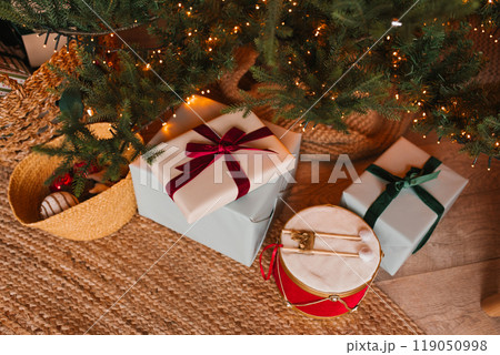 Christmas tree with presents underneath it, stacked on top of each other, with one of them being a drum. The scene is festive and joyful 119050998
