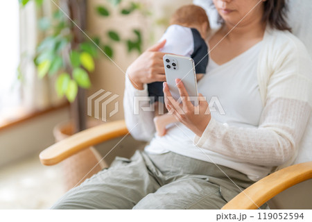 子供を抱きながらスマホをやめられない主婦 119052594