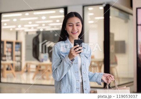 Smiling Shopper with Smartphone and Bags Celebrating Black Friday Finds 119053037