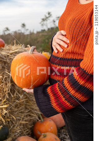 Pregnant Woman Holding Pumpkin in Hands 119053144