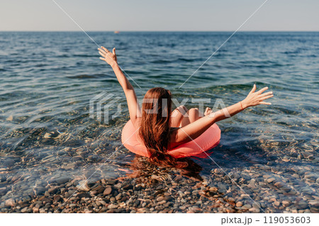 A woman is in the ocean, holding her arms up in the air and smiling 119053603