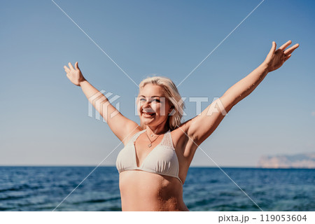 A woman in a bikini is smiling and waving at the camera 119053604