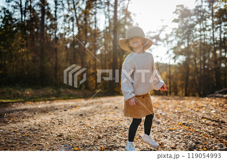 Portrait of cute girl with hat low on head in the middle autumn forest, having fun and laughing. 119054993