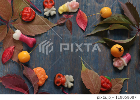 Frame of fall leaves, candy for Halloween. Holidays and food. Dessert in the shape of a pumpkin, skull, witch. Background for design. Frame of fall leaves, candy for Halloween. Holidays and food. Dessert in the shape of a pumpkin, skull, witch. Background for design. 119059087