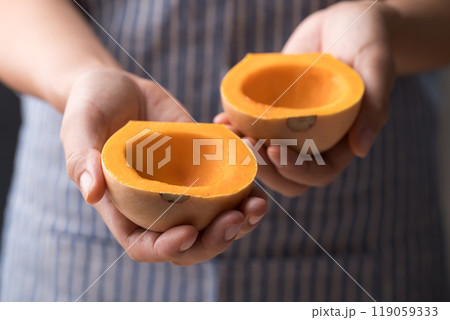 Half butternut squash pumpkin holding by woman hand for cooking Half butternut squash pumpkin holding by woman hand for cooking 119059333