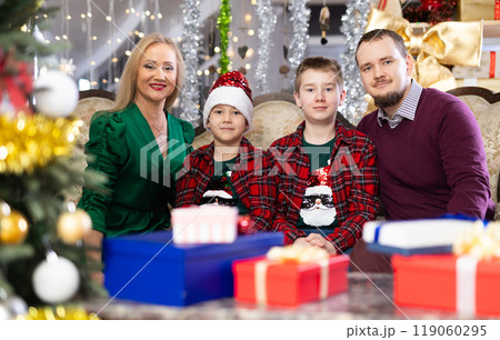 Portrait of happy family with two children celebrating Christmas next to Christmas tree 119060295