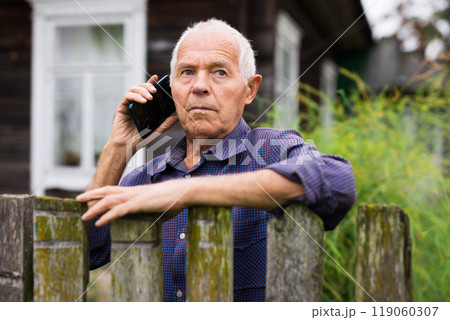 Portrait of an male farmer on backyard country house using smartphone phone for communication 119060307
