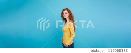 Lifestyle concept - Close up Portrait young beautiful attractive ginger red hair girl playing with her hair with shyness. Blue Pastel Background. Copy space Lifestyle concept - Close up Portrait young beautiful attractive ginger red hair girl playing with her hair with shyness. Blue Pastel Background. Copy space 119060588