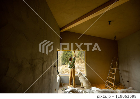 Woman paints walls while making repairment of a new house 119062699