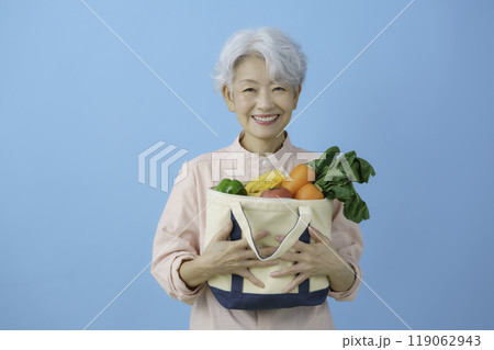 ブルーバックの緑黄色野菜を手に持つ白髪のシニア女性 ブルーバックの緑黄色野菜を手に持つ白髪のシニア女性 119062943