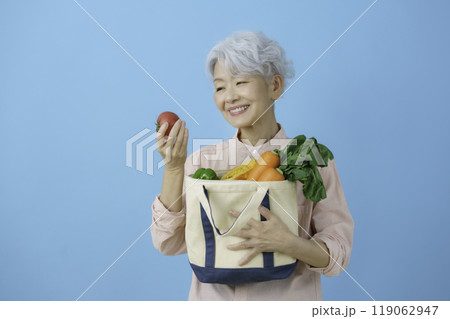 ブルーバックの緑黄色野菜を手に持つ白髪のシニア女性 ブルーバックの緑黄色野菜を手に持つ白髪のシニア女性 119062947