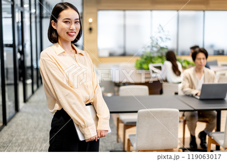 パソコンを持って笑顔でコチラを見るビジネスパーソン 119063017