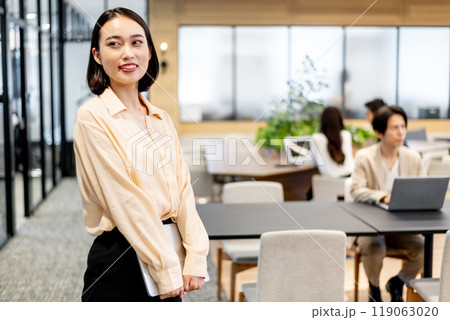 立った姿勢でノートパソコンを持っているビジネスパーソン 立った姿勢でノートパソコンを持っているビジネスパーソン 119063020