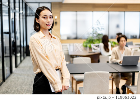 立った姿勢でノートパソコンを持って正面を見つめるビジネスパーソン 119063022