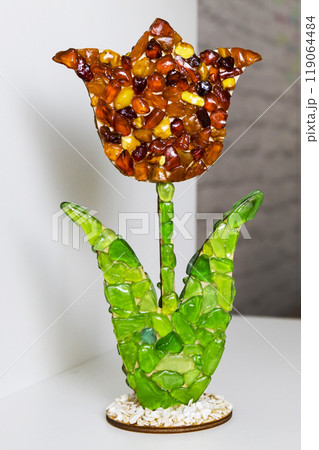 A beautifully crafted flower sculpture with a vibrant green stem 119064484