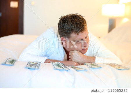Man in white robe lying on bed counting cash dollars concept of successful life Man in white robe lying on bed counting cash dollars concept of successful life 119065285