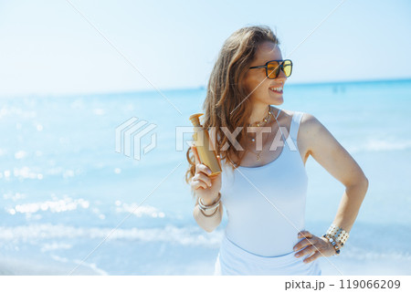 smiling stylish female on seashore with spf smiling stylish female on seashore with spf 119066209