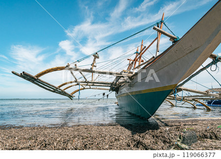Beached wooden boat on sandy shore with tires 119066377
