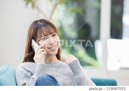 ソファに座って電話をかける女性 ソファに座って電話をかける女性 119067031