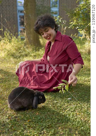 a young plus-size woman plays with her pet rabbits in the garden of a student dormitory a young plus-size woman plays with her pet rabbits in the garden of a student dormitory 119067120