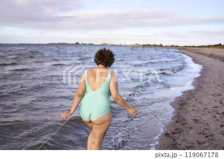 a young plus-size woman is engaged in winter swimming and warming up by the sea a young plus-size woman is engaged in winter swimming and warming up by the sea 119067178
