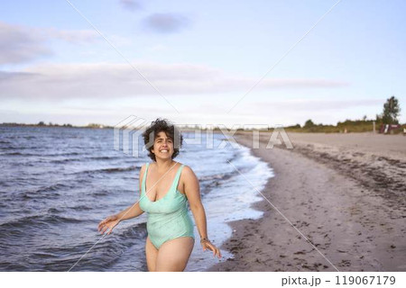 a young plus-size woman is engaged in winter swimming and warming up by the sea a young plus-size woman is engaged in winter swimming and warming up by the sea 119067179