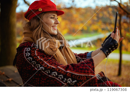 woman video chatting while sitting on bench in city park 119067308