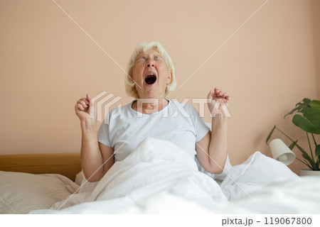 Portrait of beauty Caucasian 50s 60s woman awaking, wake up on the bed. Young beautiful female stretching her arms in fresh early morning, relax peaceful morning routine yawn concept banner 119067800