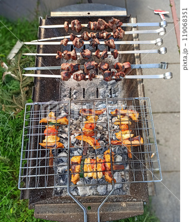 Delicious skewers grilling over charcoal in a backyard setting during a sunny afternoon 119068351