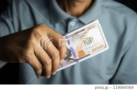 Hand holding money, one hundred dollar bill in man's hand to pay and give. 119069369