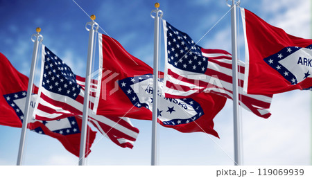 Arkansas state flags waving with the American flags on a clear day 119069939