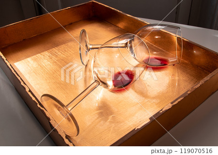 Used wine glasses, two half empty glasses of red wine on a golden tray background 119070516