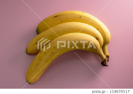 Three yellow bananas on a pink background Three yellow bananas on a pink background 119070517