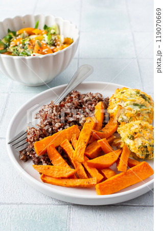 A healthy and filling meal of brown rice, baked sweet potato and squash chickpea pancakes, packed with flavor and nutrients, fresh salad of tomatoes and cucumbers A healthy and filling meal of brown rice, baked sweet potato and squash chickpea pancakes, packed with flavor and nutrients, fresh salad of tomatoes and cucumbers 119070669