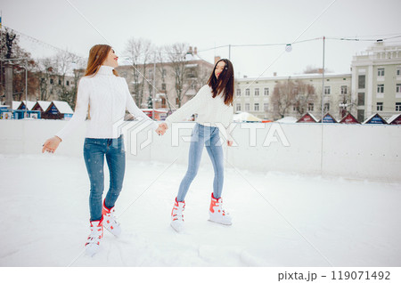 Girls in a winter city. Beautiful ladies in a white sweater. Women in a ice arena 119071492