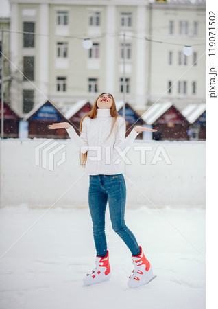 Girl in a winter city. Beautiful lady in a white sweater. Woman in a ice arena 119071502