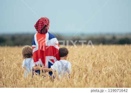 Family of Patriots - Woman Mother with boys kids holding great britain national flag In Rural Wheat Field. Democracy, future celebration, UK banner, Remembrance Day, election 119071642